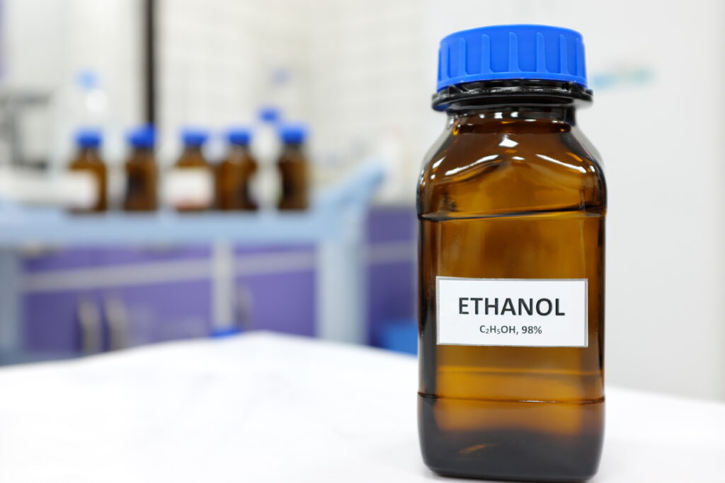 A bottle sitting on lab table with a label saying "Ethanol"