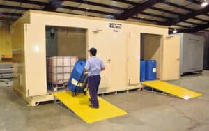 Man wheeling hand truck with barrel of chemicals into shipping container