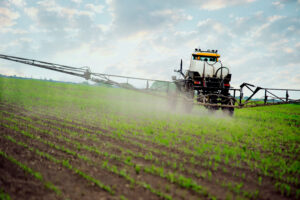 a tractor sprays crops with fertilizer which is a part of importance of safe agricultural chemical storage