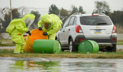 Two workers simulate a hazardous chemical spill clean up from improper containment