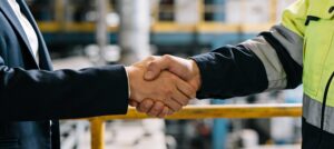 A man in suit and a man in reflective vest shake hands